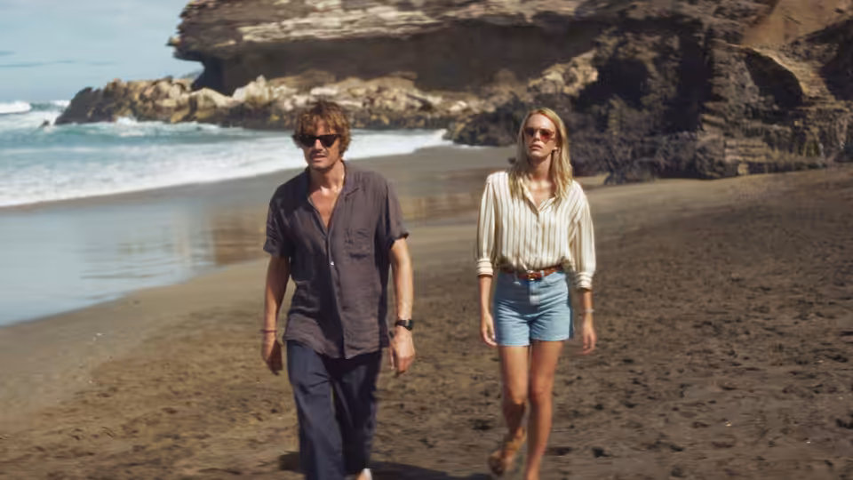 Tom (Sam Riley) and Anne (Stacy Martin) walk along a beach beneath rocky cliffs
