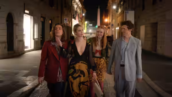 Four young adults walk together along a city street at night