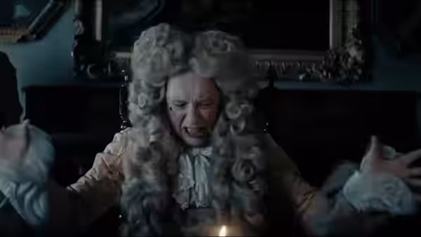 A powdered-wig man throws his arms wide and shouts in a dark room