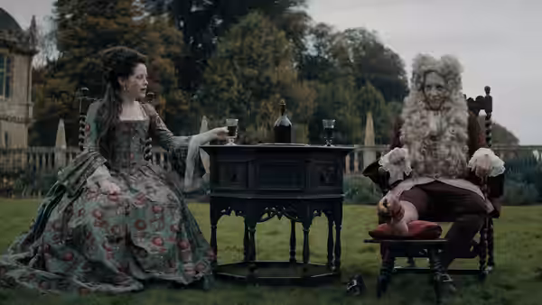 A woman in a floral gown offers a glass to a powdered-wig man in the garden