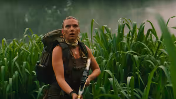 Zora Bennett (Scarlett Johansson) holding a rifle in tall green plants