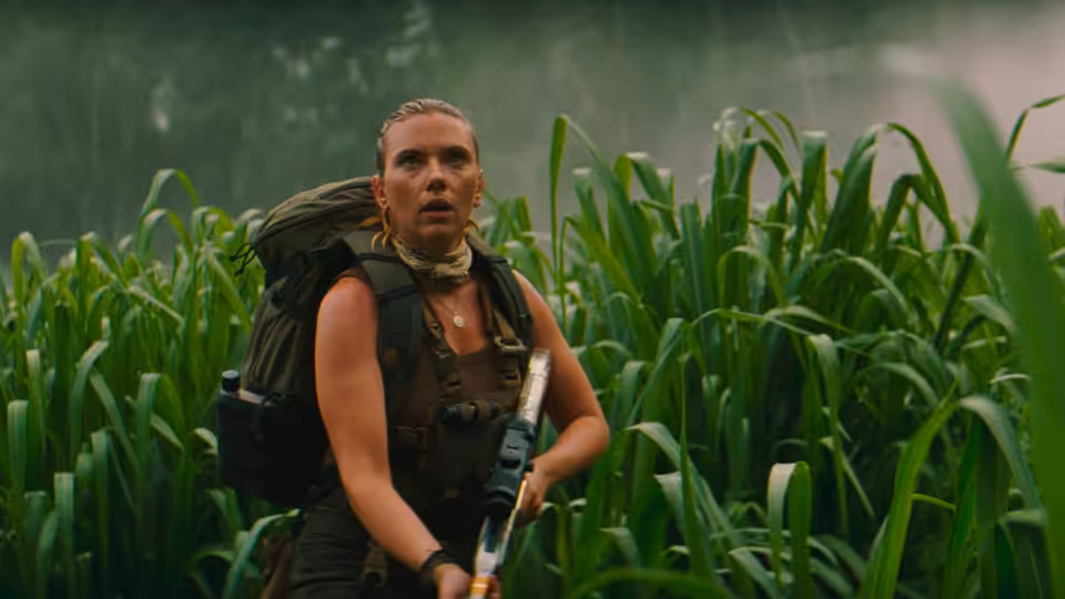 Zora Bennett (Scarlett Johansson) holding a rifle in tall green plants