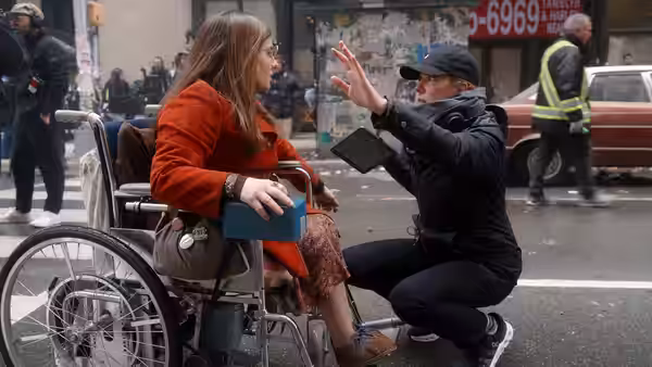 Judy Heumann (Ruth Madeley) speaks with a kneeling demonstrator in the street