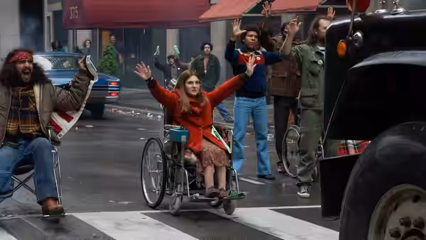 Judy Heumann (Ruth Madeley) and demonstrators raise their hands in the street