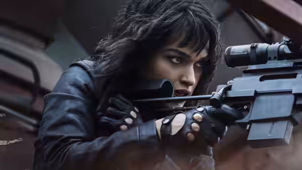 A woman aims a scoped rifle from behind cover
