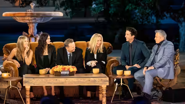 The six Friends cast members and James Corden sit together on the Central Perk set