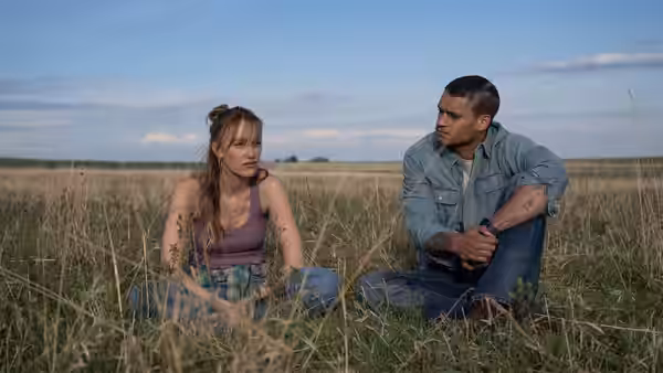 Kenna Rowan (Maika Monroe) and Ledger Ward (Tyriq Withers) sit together in a grassy field