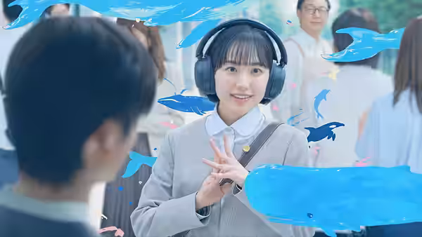 A young woman wearing headphones gestures toward a seated man amid blue fish graphics