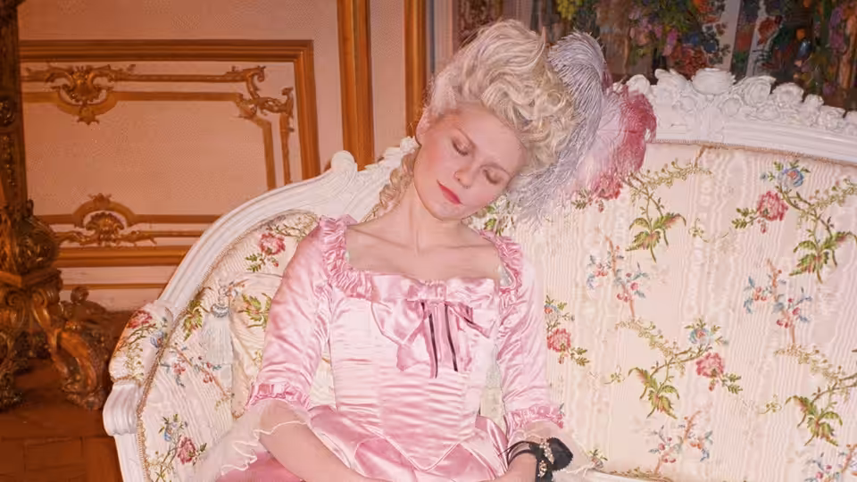 Marie Antoinette (Kirsten Dunst) reclines on a floral settee in an ornate room