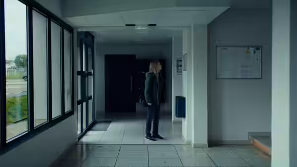 A woman stands alone in a bright institutional hallway