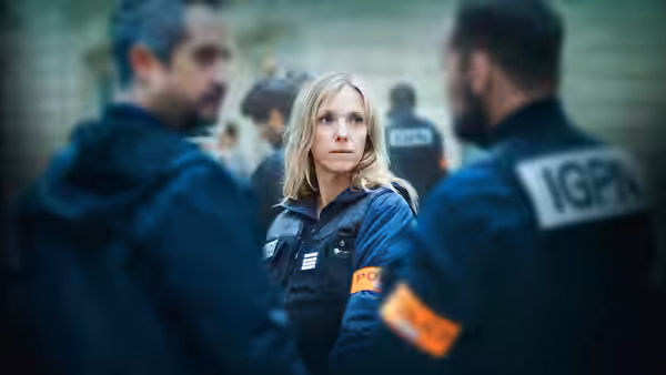 Stéphanie Bertrand (Léa Drucker), wearing an investigation jacket, stands among uniformed officers