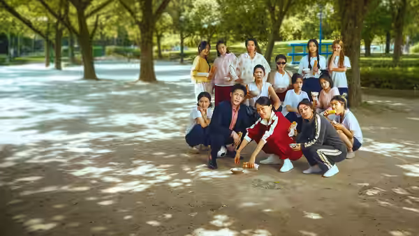 A group of teammates pose together beneath the trees in a park