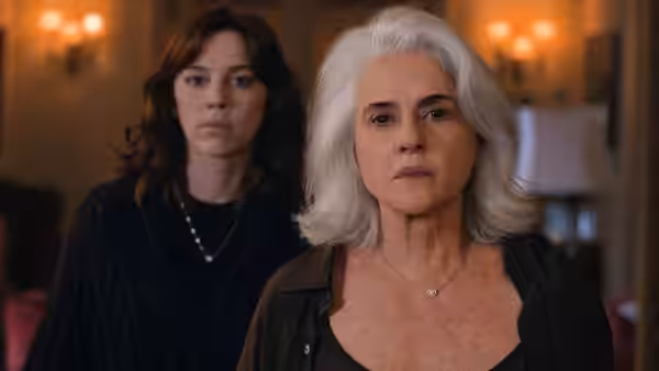 Lúcia Rossetti (Marieta Severo) stands before Maíra Rossetti (Alice Wegmann) in a warmly lit room