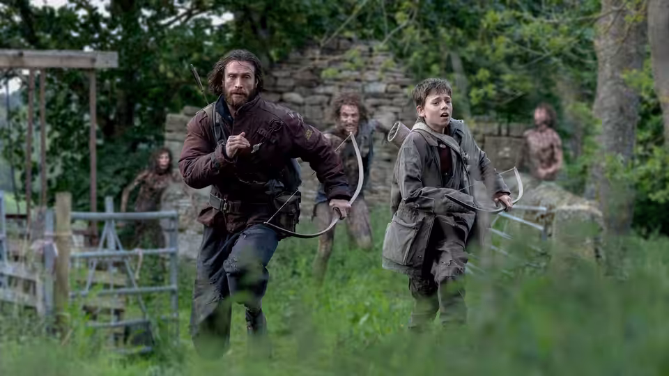 Jamie (Aaron Taylor-Johnson) and Spike (Alfie Williams) running across a grassy field