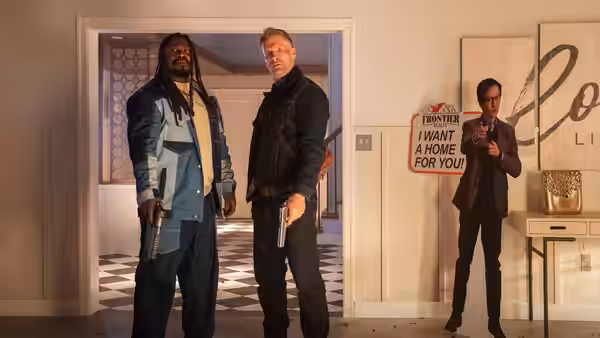 Two armed men stand in a doorway while Marvin Gable (Ke Huy Quan) watches from inside