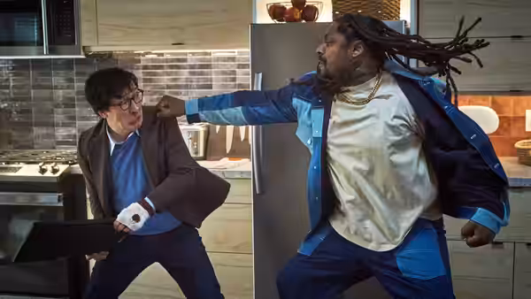 Marvin Gable (Ke Huy Quan) braces as a large, dreadlocked man swings at him in a kitchen