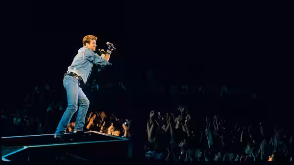 George Michael sings from a runway stage as fans reach toward him