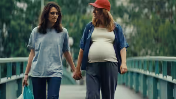 Two women hold hands while walking across a pedestrian bridge