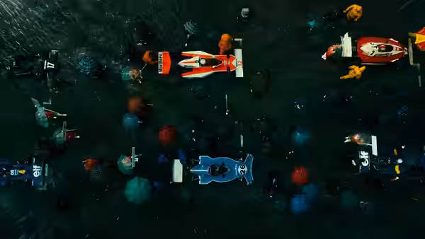 Formula One cars lined up on a rain-soaked starting grid with umbrellas