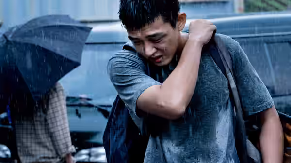 Lee Jong-su (Yoo Ah-in) grimaces in heavy rain beside a car