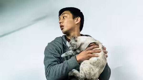 Lee Jong-su (Yoo Ah-in) holds a cat while looking upwards indoors