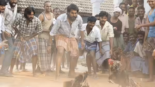 Men gather around as two contestants crouch at a village rooster fight