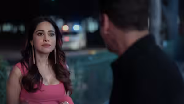 A woman in a pink dress faces a man beside a railing at night