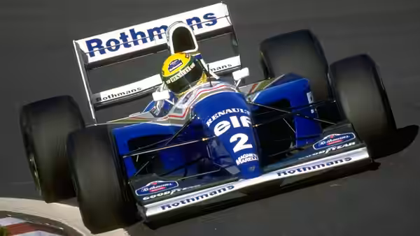 a driver in a blue formula one car speeding on the track