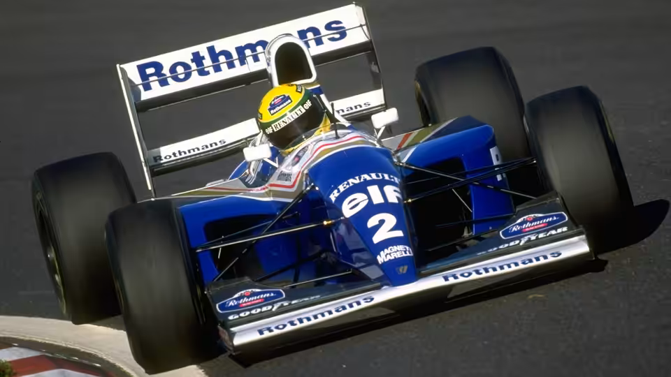 a driver in a blue formula one car speeding on the track