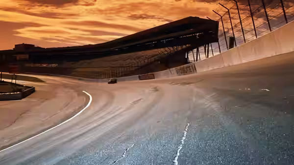 a lone race car driving on the empty track at sunset