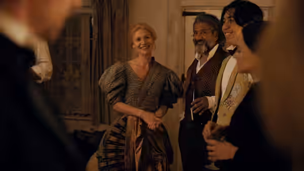 Cora Seaborne (Claire Danes) joins guests in period dress at an evening gathering
