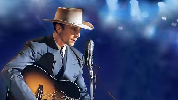 Hank Williams (Tom Hiddleston) sings into a microphone while playing guitar onstage