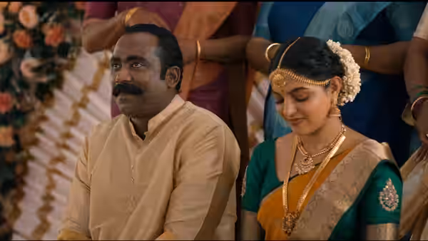 A mustached man sits beside a bride in traditional attire during a ceremony