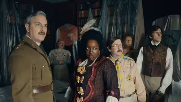 The Captain, Kitty and Pat stand among other ghosts in a cluttered room