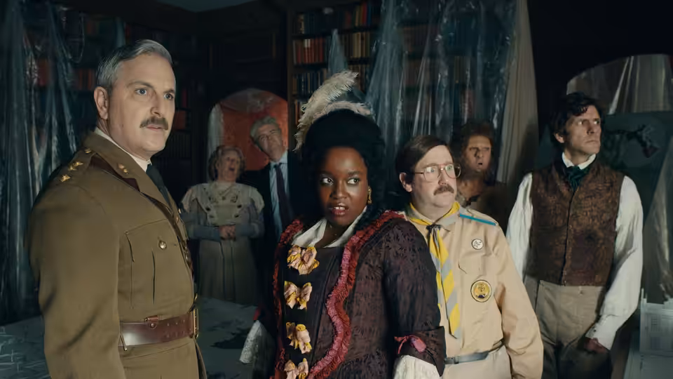 The Captain, Kitty and Pat stand among other ghosts in a cluttered room