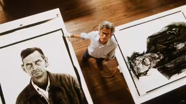 Richard Avedon stands between oversized portrait prints in a photography studio
