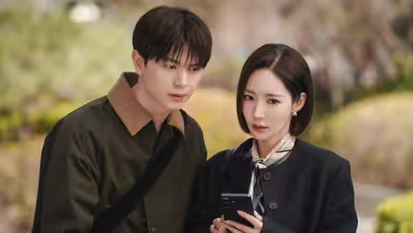 A woman and a man stand outdoors, studying a phone together