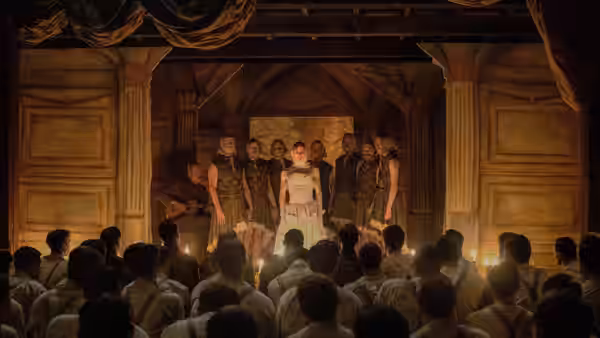 Uniformed men perform on a stage before a seated audience