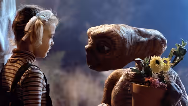 Gertie (Drew Barrymore) facing an alien holding a potted plant with flowers