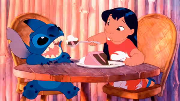 Lilo offers Stitch a bite of cake at the kitchen table