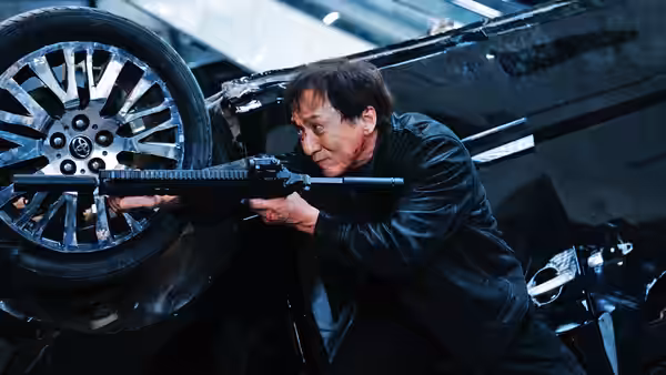 Wong Tak Chung (Jackie Chan) aims a rifle from beneath an overturned car