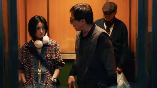 A young woman wearing headphones stands beside a man in an elevator