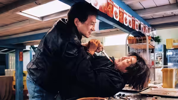 Wong Tak Chung (Jackie Chan) grapples with a man across a restaurant counter