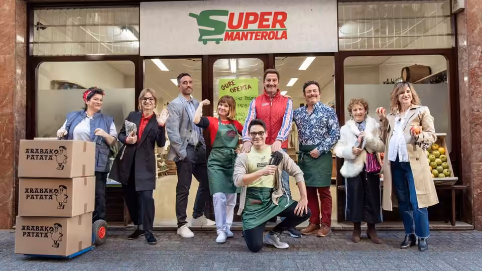 A group of shop workers pose outside a supermarket beside stacked potato boxes