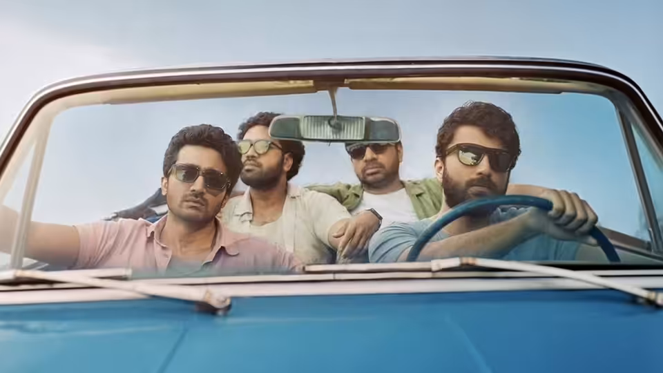 Four men ride in a blue convertible, one steering while the others sit beside him