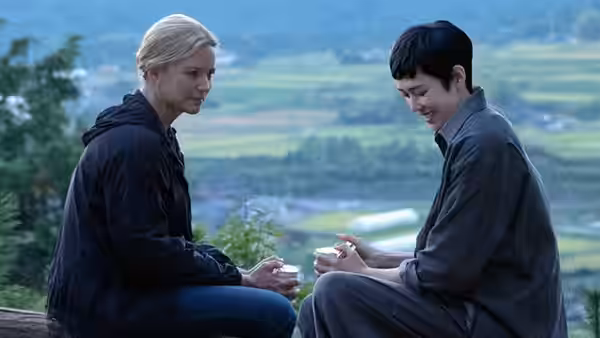 Marie Lou-Fontaine (Virginie Efira) and Mari Morisaki (Tao Okamoto) sit together overlooking a rural valley