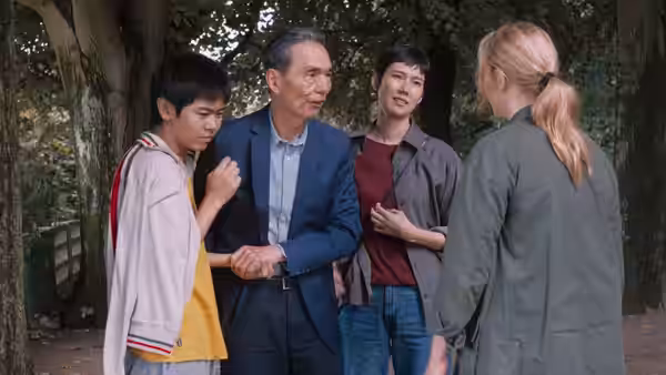 A man and two boys speak with Marie Lou-Fontaine (Virginie Efira) beneath the trees