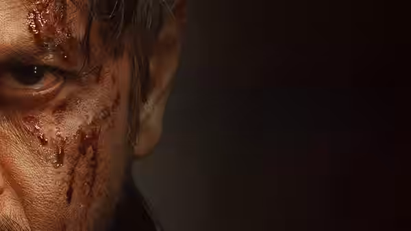 A close-up shows a man's bloodied face against a dark background