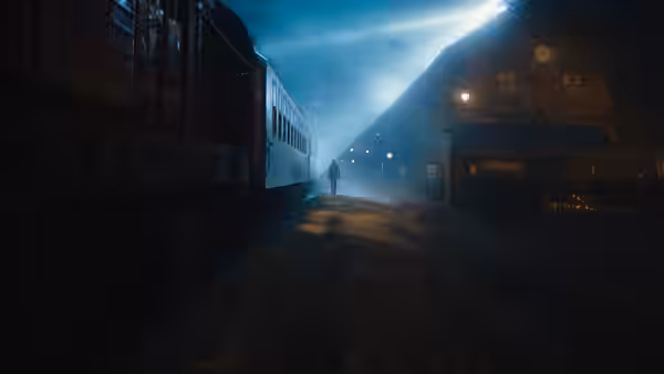 a lone figure on snowy tracks before a stationary train at night