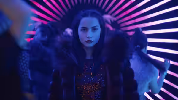 Eve (Ana de Armas) standing amid dancers under pink neon lights